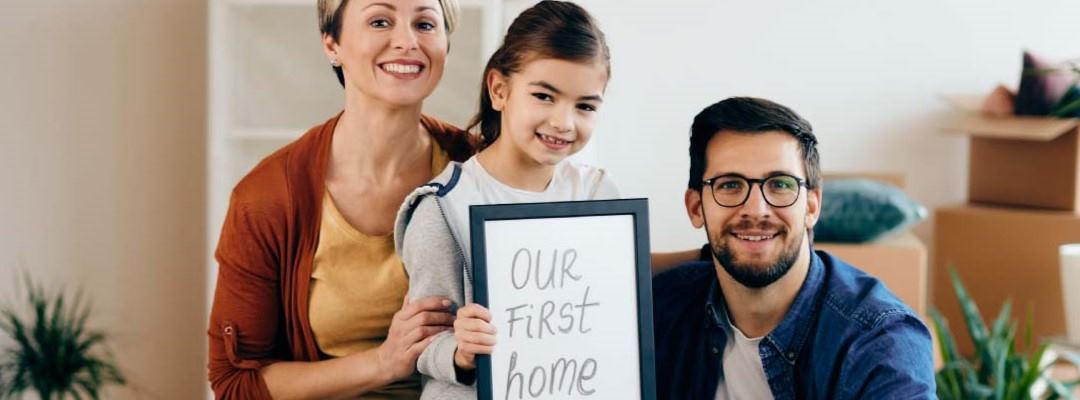 Happy family holding an our first home sign