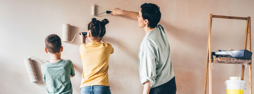 Woman and kids painting a wall.