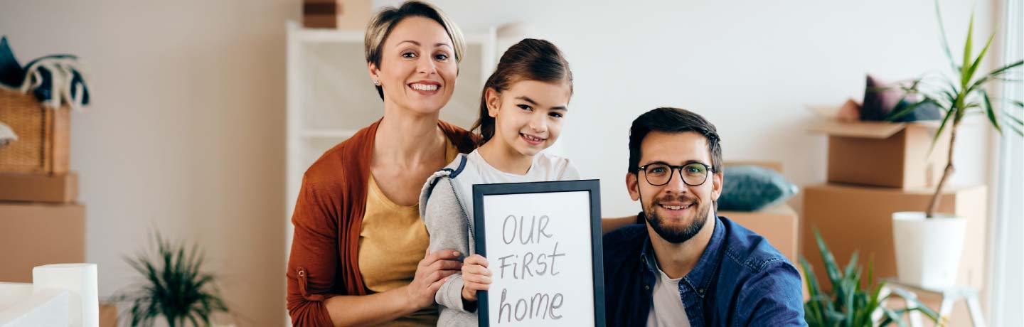 Happy family holding an our first home sign