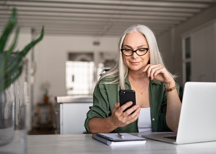 Older person smiling looking at their phone 